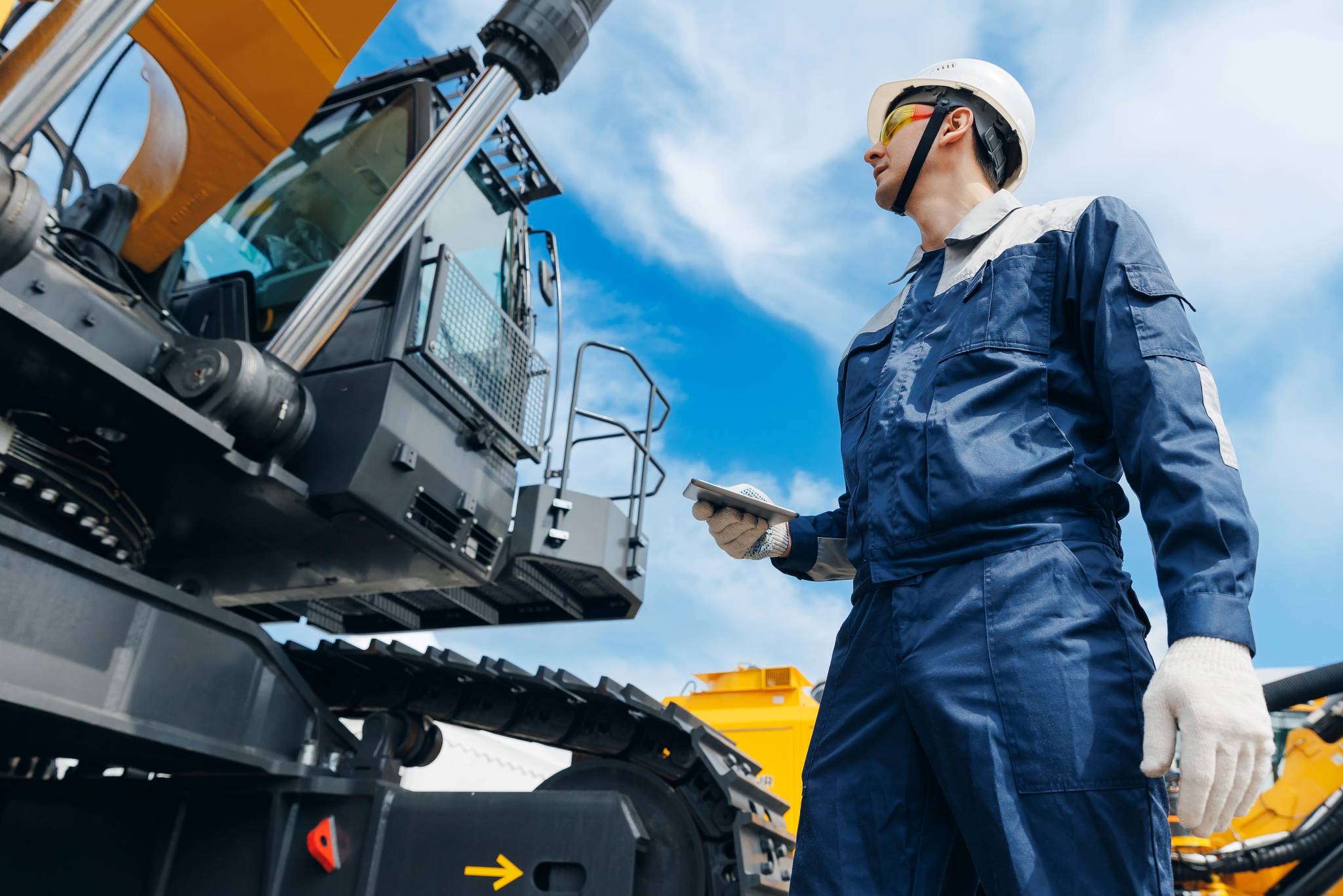 caucasian male engineer use tablet conputer for AI control mining heavy machinery and equipment.